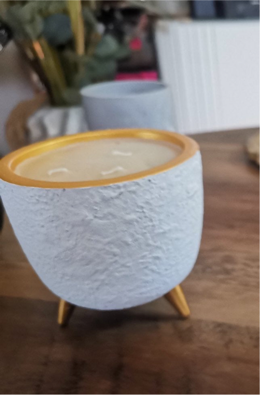 Bougie dans un pot blanc avec trois pieds dorés